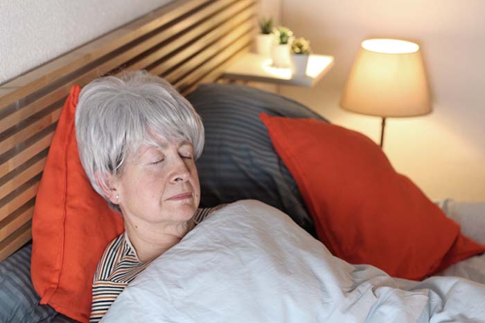 elderly woman fast asleep with bedroom light on